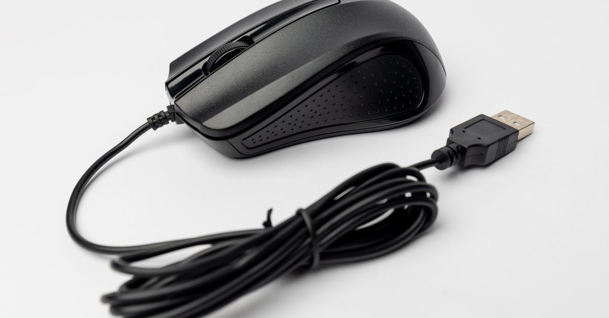 Close-up of a black wired computer mouse on a white background, showcasing its design and connection cable.